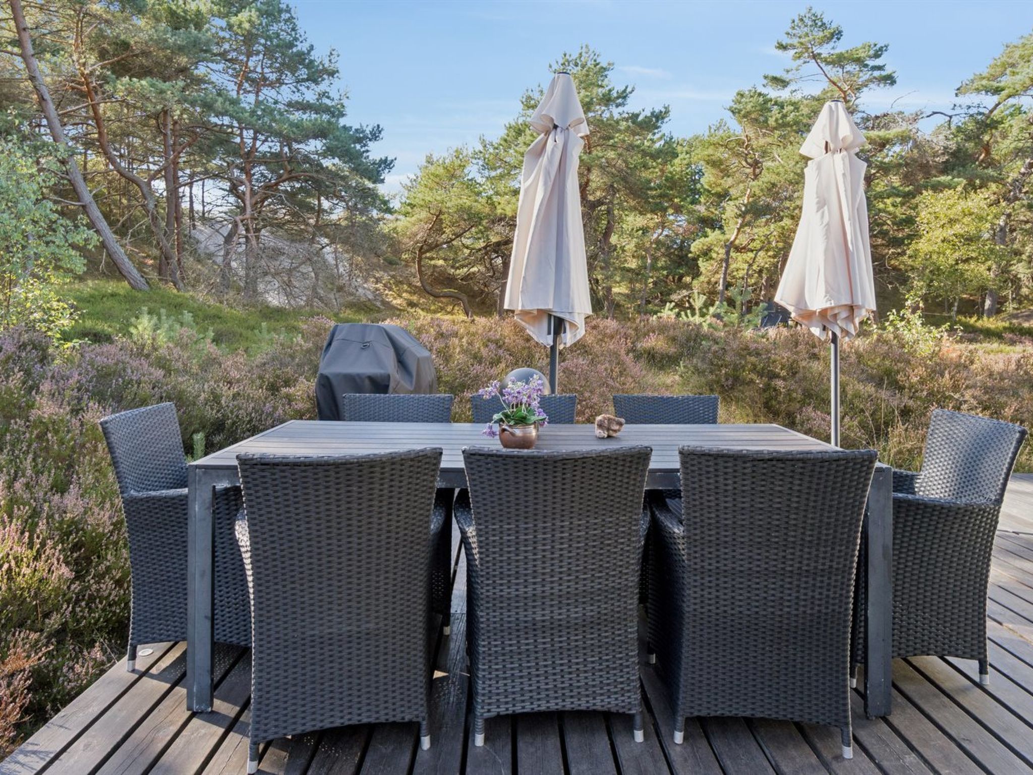 A deck with a table and chairs, surrounded by trees.