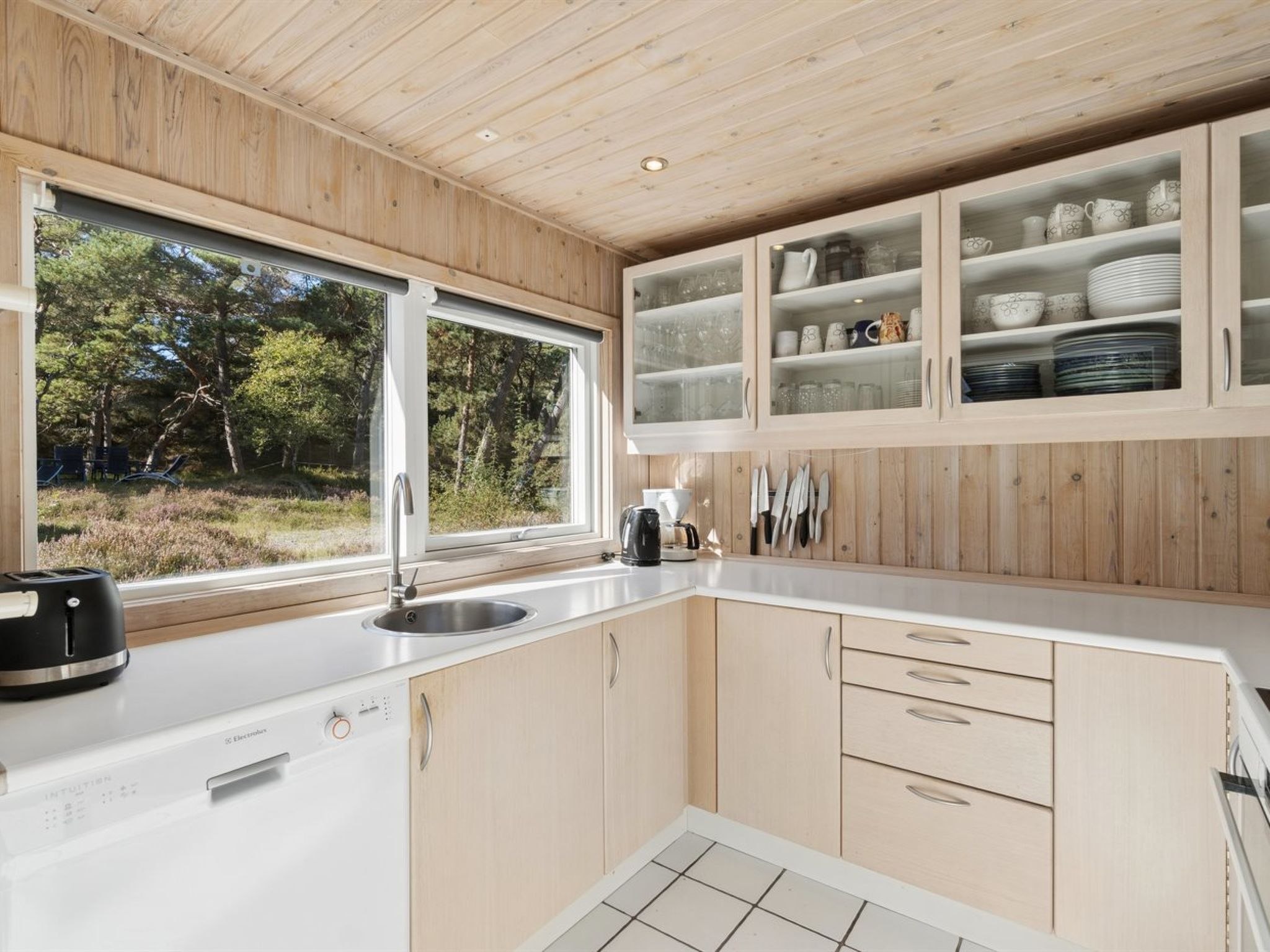 Eine moderne Küche mit Holdekor, einem eingebauten Spülbecken und einem Fenster mit Blick auf ein bewaldetes Gebiet.
