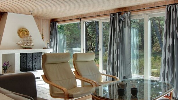 A modern living room with a glass table, two leather armchairs, a sofa, and a fireplace with a decorative ship model. - "Minka" - 300m from the sea by Interhome (Nexø)
