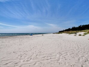 A sandy beach with a tent and people in the distance.