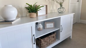 A white cabinet with a vase, a framed picture, a small plant, and a wicker basket. - NEW Cozy Home in Historic Venice (Venice)
