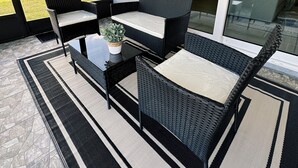 A patio area with wicker furniture, a small table, and a potted plant. - NEW Cozy Home in Historic Venice (Venice)