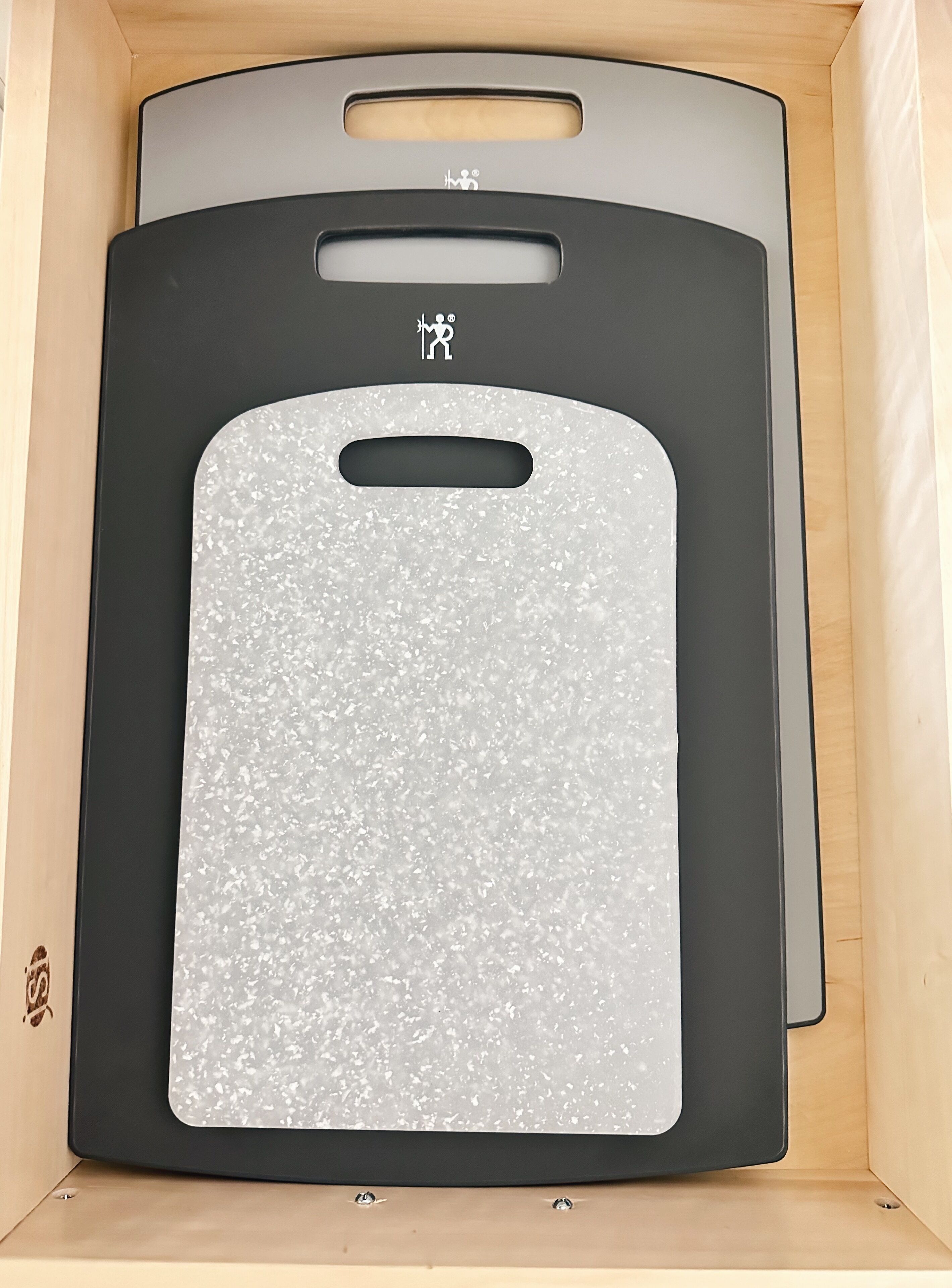 A wooden cabinet with a black and white speckled cutting board inside.