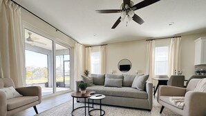 A spacious living room with a grey sofa, two armchairs, a coffee table, and a ceiling fan. - NEW Cozy Home in Historic Venice (Venice)