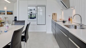 A modern kitchen with white cabinetry, a built-in oven, and a stainless steel sink. - "Botolphus" - 20m from the sea by Interhome (Nexø)