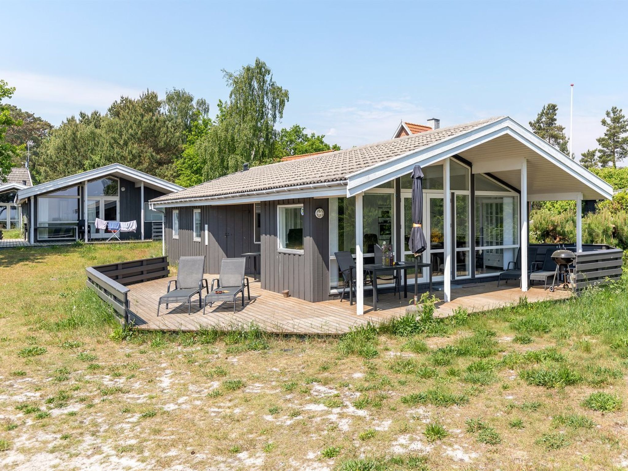 A modern vacation home with a covered patio, outdoor seating, and a deck.