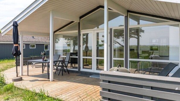 A modern house with a covered patio, large glass windows, and a wooden deck. - "Botolphus" - 20m from the sea by Interhome (Nexø)