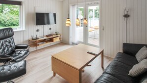 A modern living room with a wooden coffee table, black leather sofa, and a TV mounted on the wall. - "Antigona" - 250m from the sea by Interhome (Nexø)