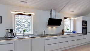 A modern kitchen with white cabinets, a built-in oven, and a flat-screen TV. - "Antigona" - 250m from the sea by Interhome (Nexø)