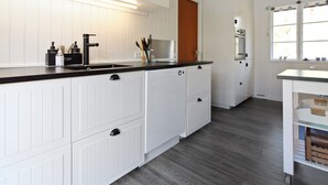 A modern kitchen with white cabinetry, a black countertop, and a wooden door. - "Ronja" - 300m from the sea by Interhome (Nexø)