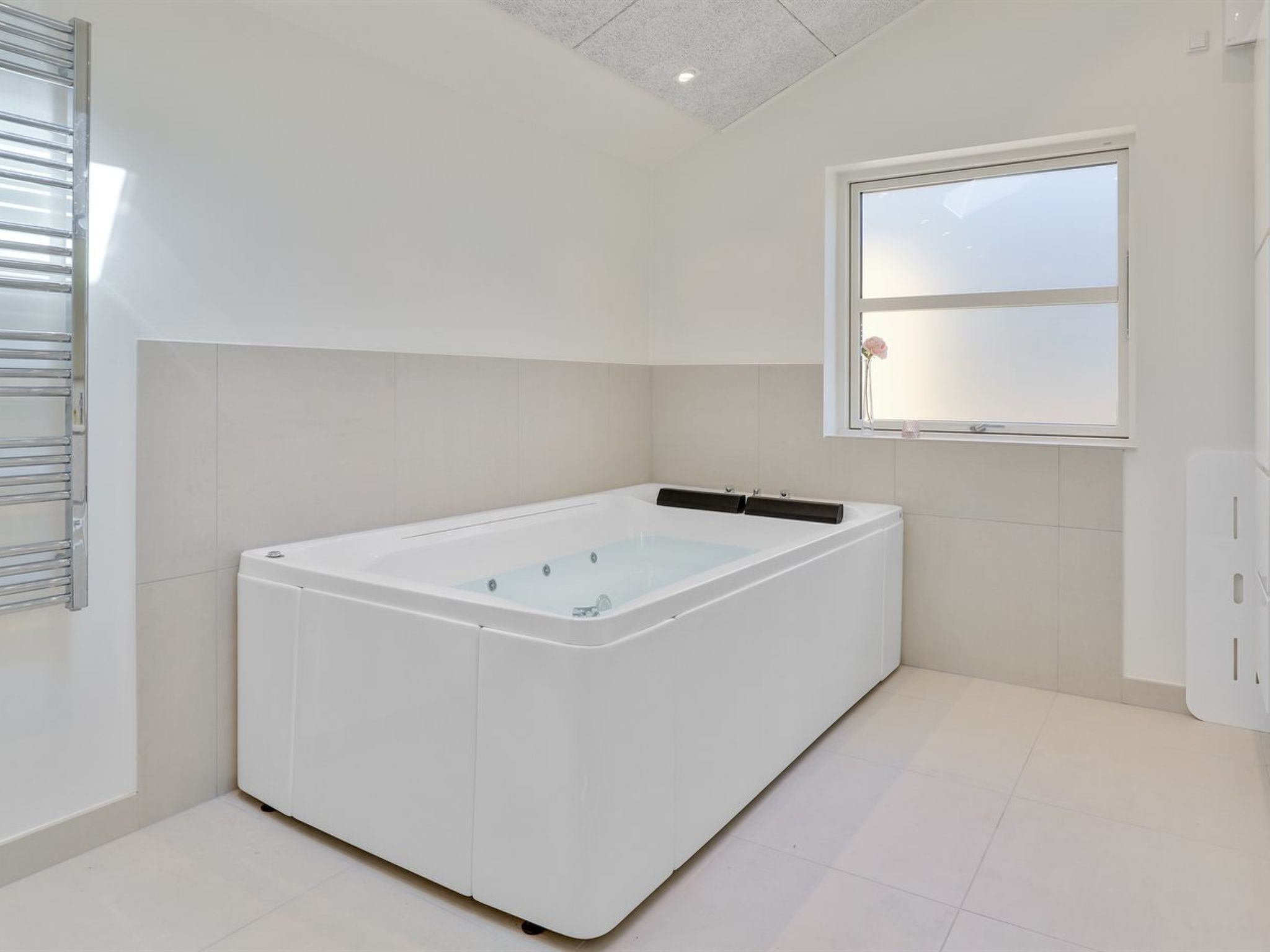 Un baño moderno con una bañera grande, una ventana con vistas y un perchero para toallas.