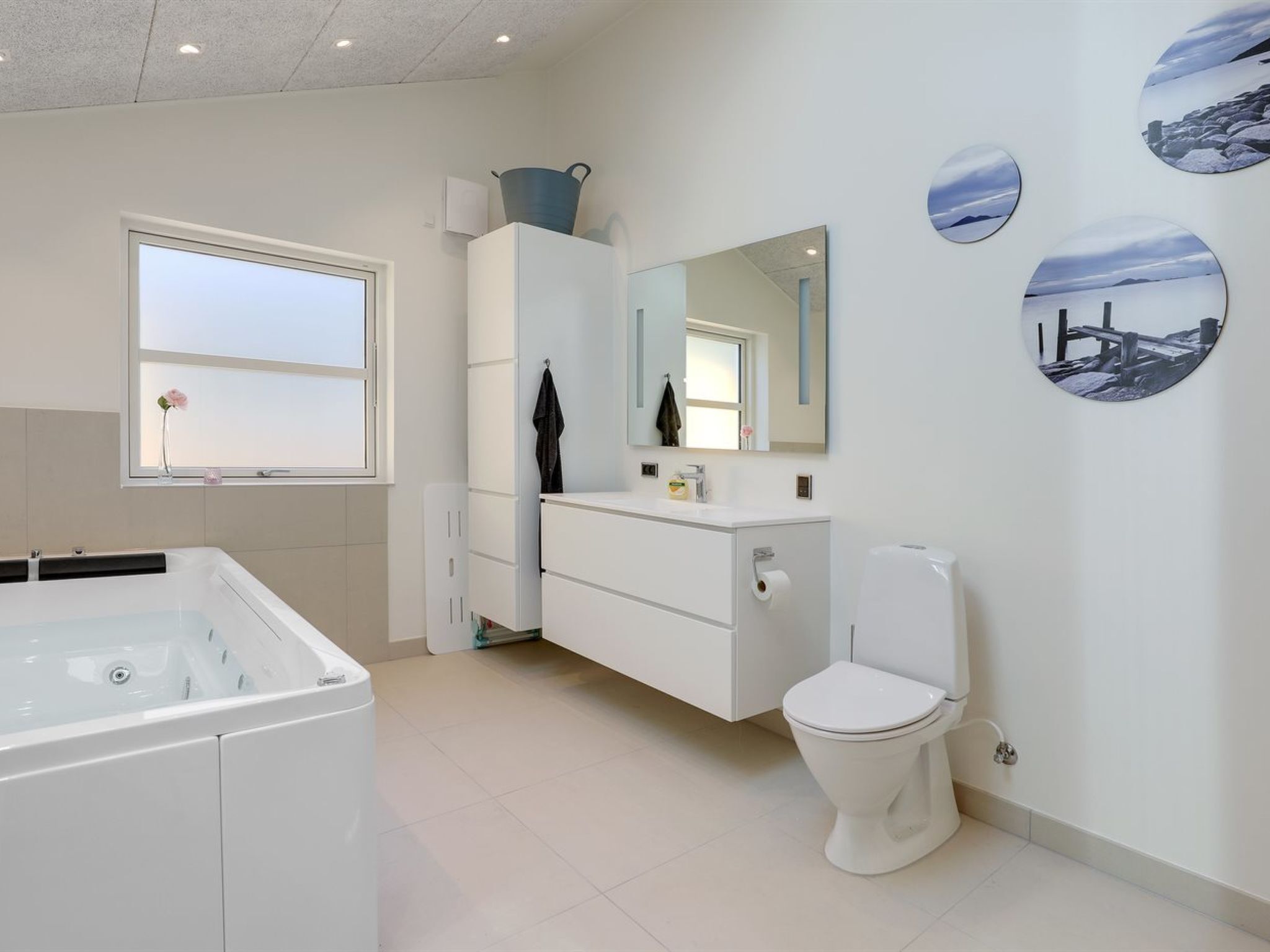 A modern bathroom with a bathtub, toilet, vanity, and a large mirror.