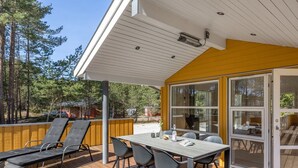 An outdoor patio with a table and chairs, a covered area with a roof, and a view of the surrounding forest. - "Arndis" - 600m from the sea by Interhome (Nexø)