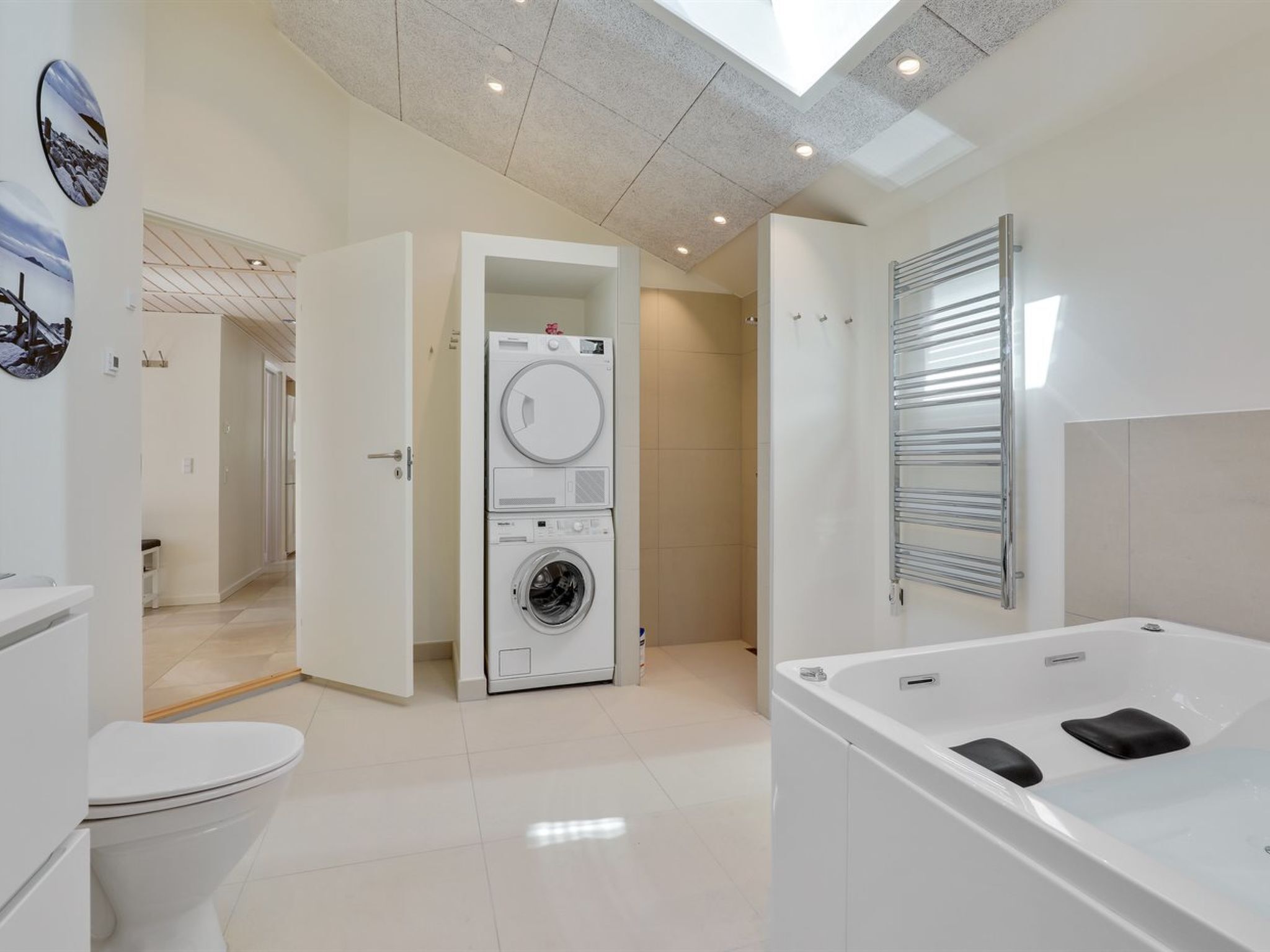 A modern bathroom with a toilet, a washing machine, and a bathtub.