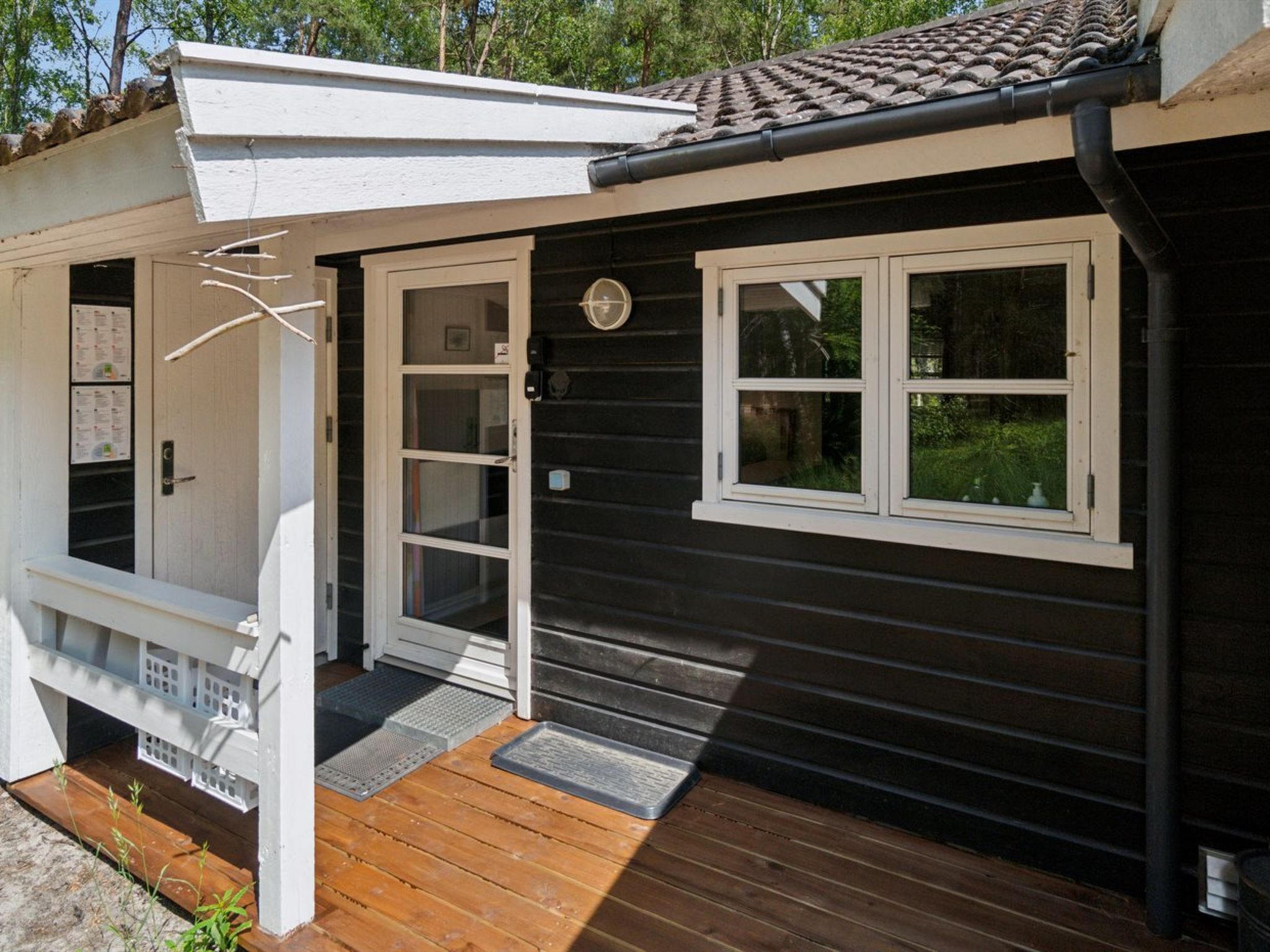 A small, single-story building with a dark exterior, white trim, and a wooden deck.