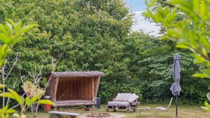 A rustic outdoor seating area with a wooden bench, a small table, and a fire pit. - "Hansen" - 5.2km from the sea by Interhome (Aakirkeby)
