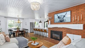 Uma sala de estar moderna com lareira, área de jantar e cozinha.