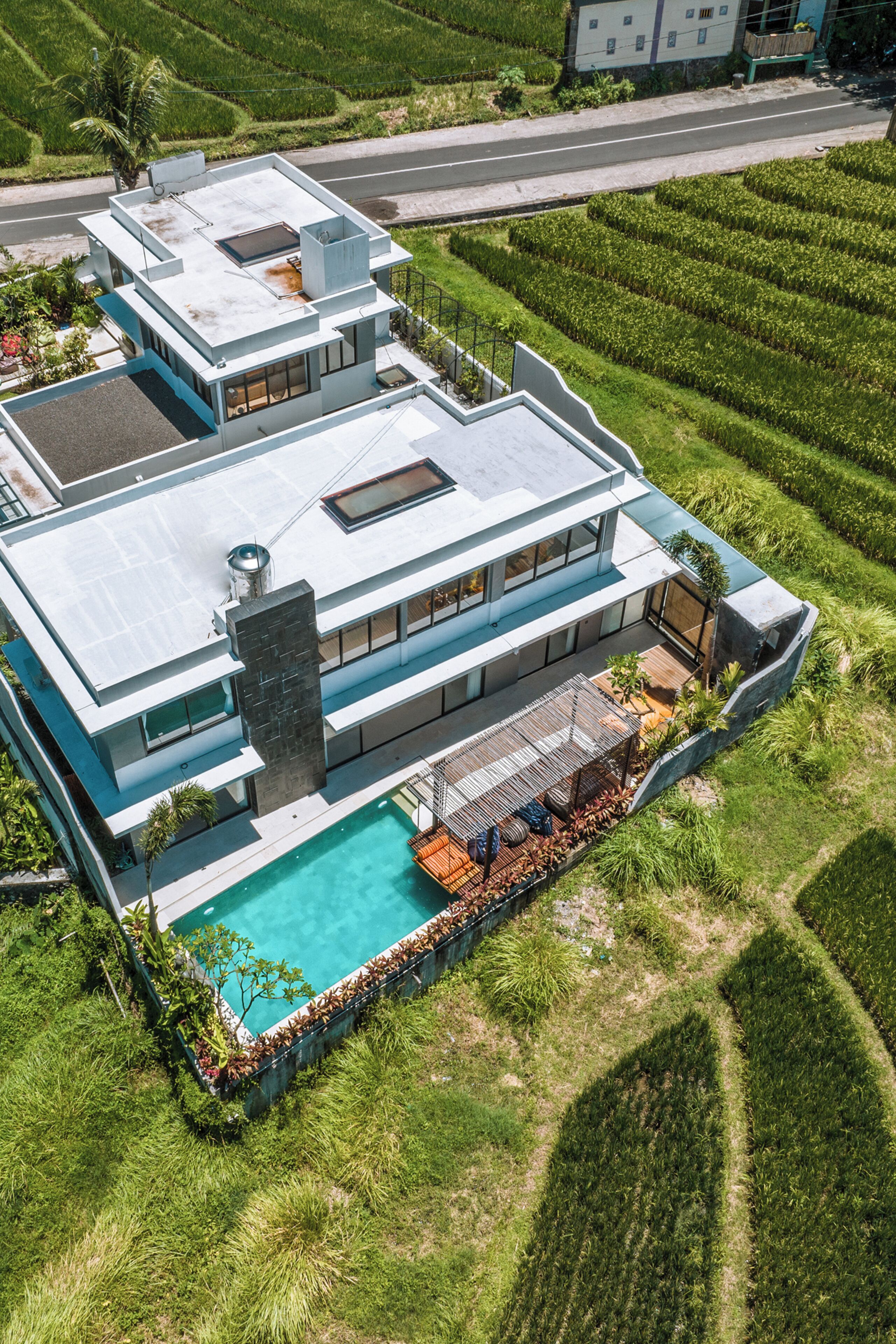 A modern two-story house with a rooftop pool and a large garden.