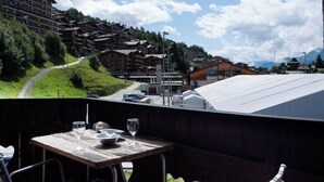 Ein Restaurant mit gedecktem Tisch, mit Blick auf eine gebirgige Landschaft und traditionelle Holzhäuser.