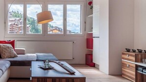 Ein modernes Wohnzimmer mit einer Couch, einem Couchtisch und Blick auf Gebäude durch große Fenster.