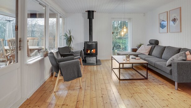 Ein gemütliches Wohnzimmer mit Kamin, Holzboden und einem grauen Sofa.