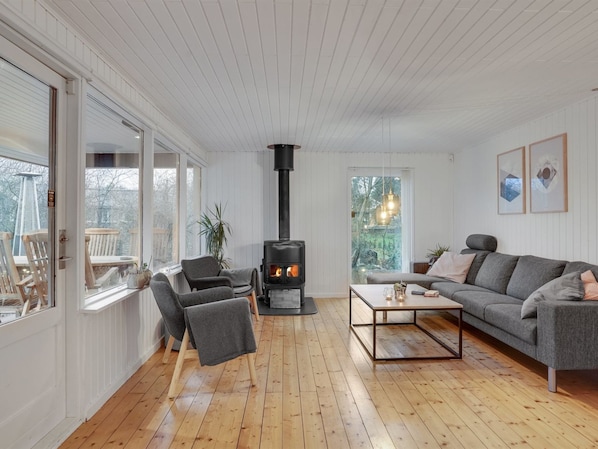A cozy living room with a fireplace, wooden flooring, and a grey sofa.