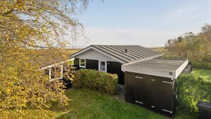 Une maison moderne avec un toit en pente, un petit garage attenant et une pelouse bien entretenue.