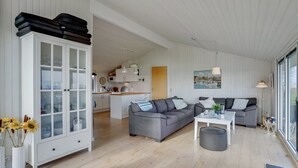 Un salon moderne avec un canapé gris, un meuble blanc aux portes vitrées et un plancher en bois.