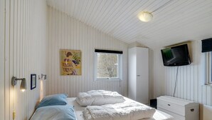 Une chambre à coucher avec un lit, une commode, un téléviseur et une fenêtre.