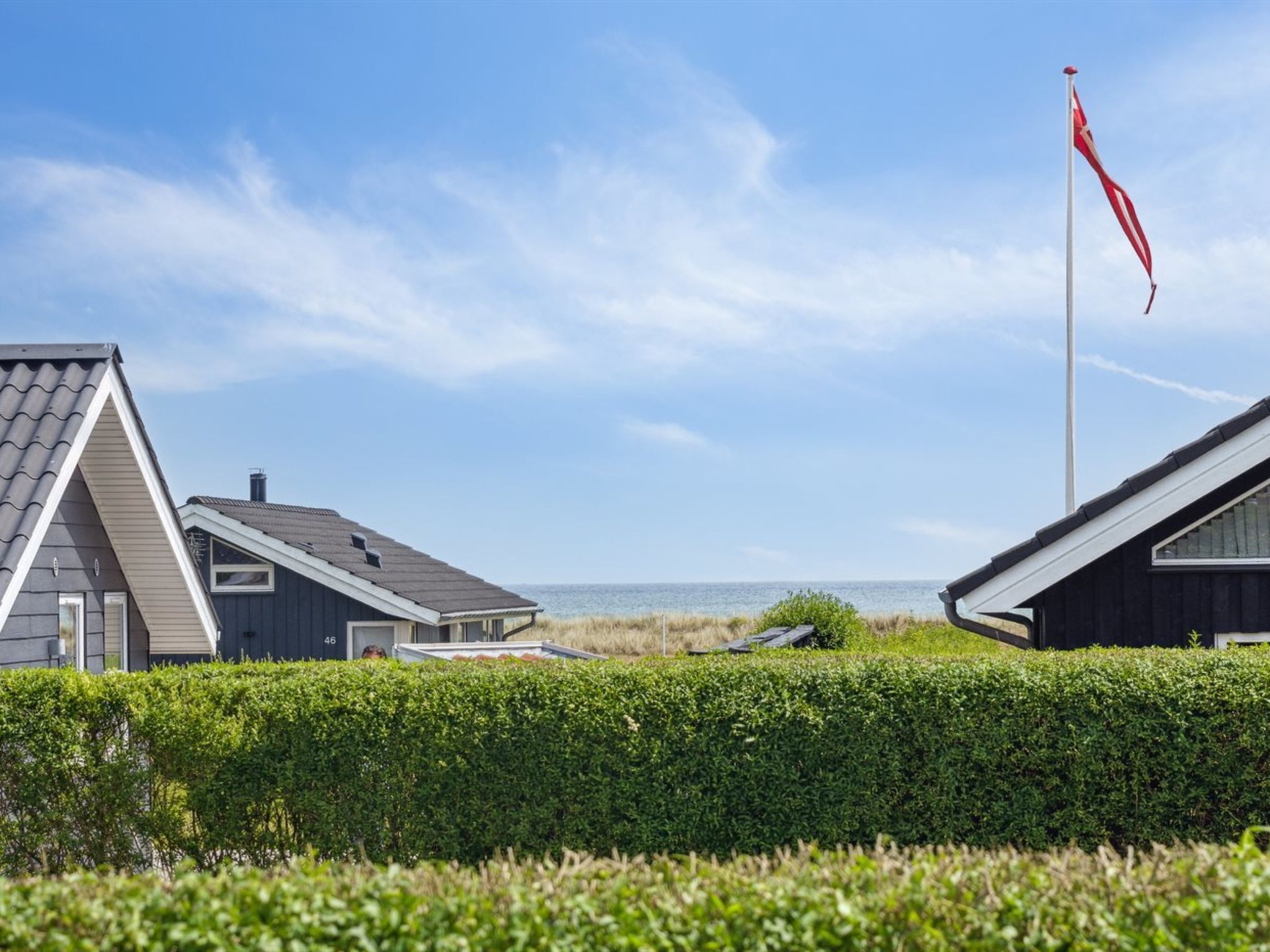 En kystejendom med flere bygninger, et flag og en uhindret havudsigt.