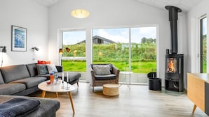 Ein modernes Wohnzimmer mit Sofa, Sessel und Kamin.