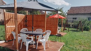 A wooden deck with a table and chairs, a covered seating area, and a swing set.