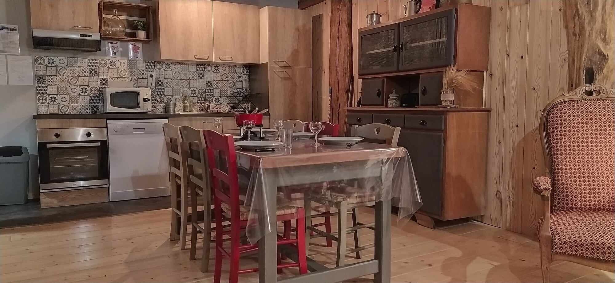 Une cuisine avec des meubles de rangement en bois, un four à micro-ondes, un four traditionnel et une table à manger pour quatre personnes.