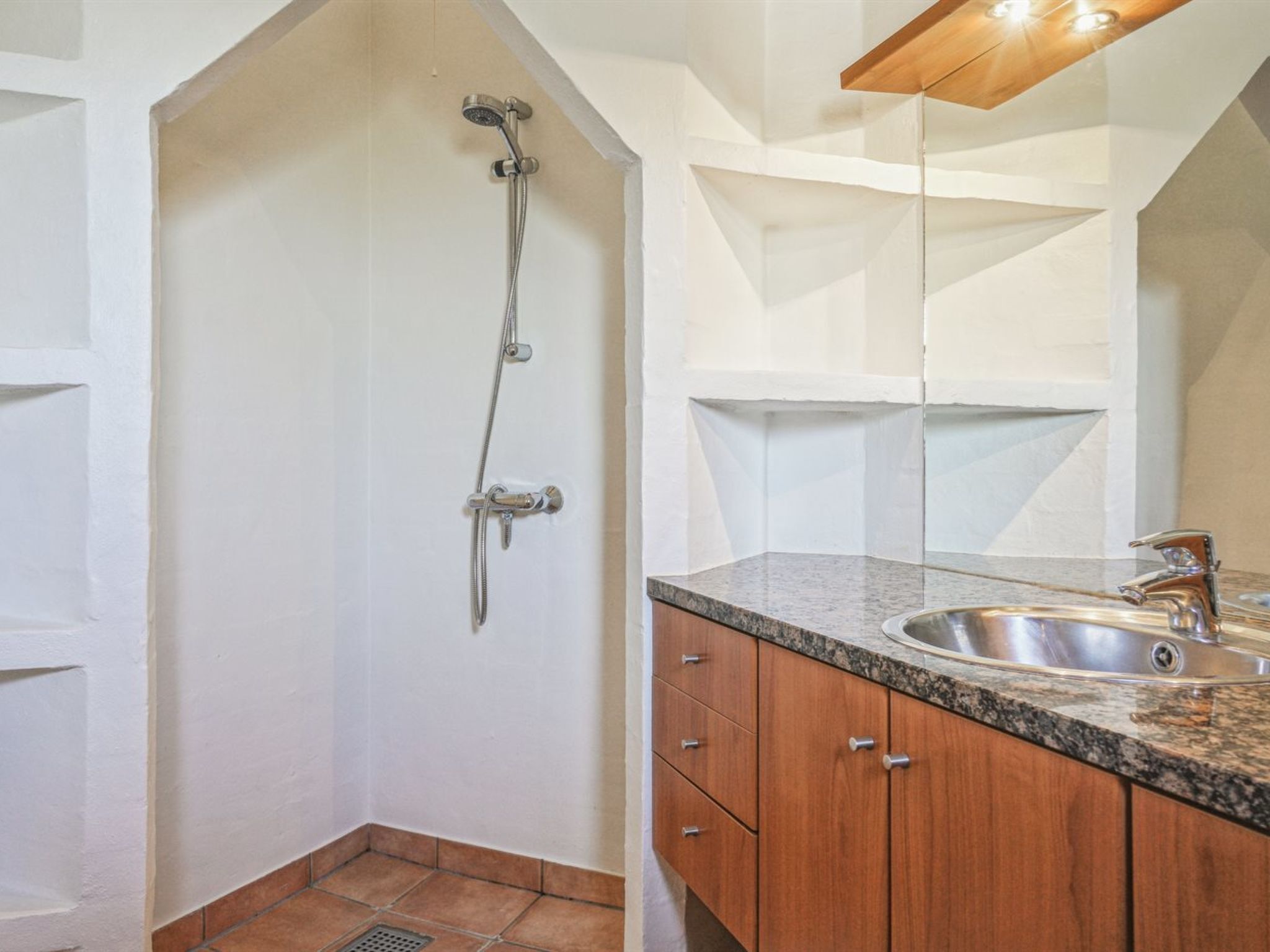 A bathroom with a shower, a sink, and wooden cabinets.