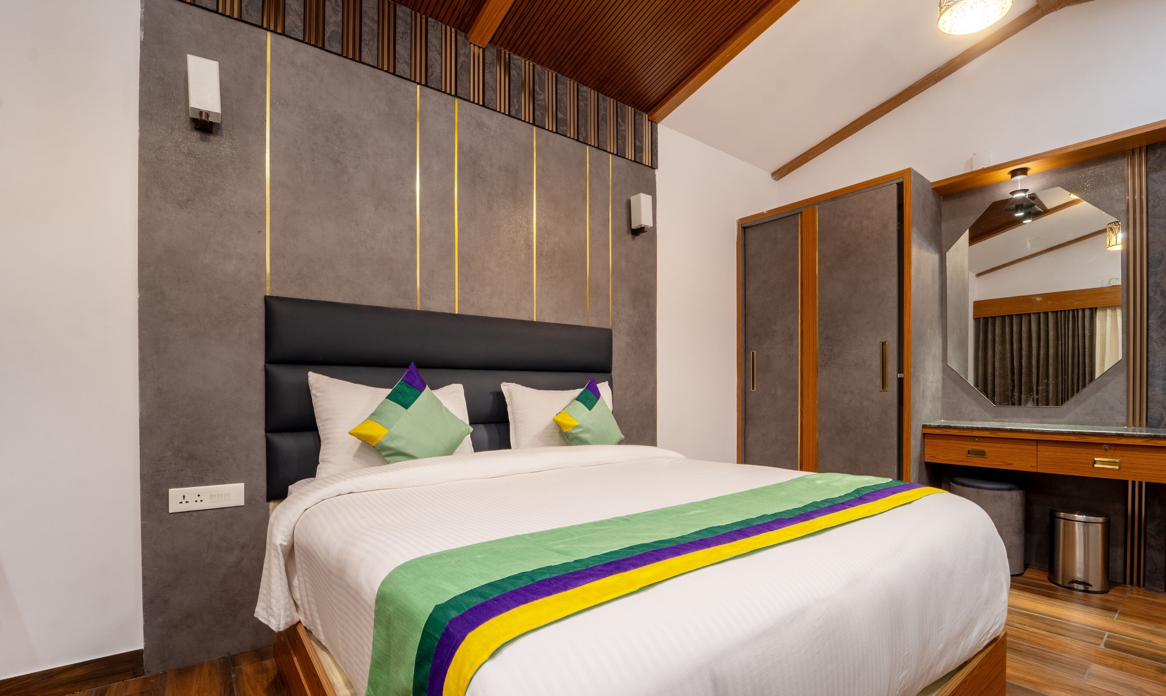 Quarto de hotel moderno com uma cama grande, teto de madeira, guarda-roupa embutido e um espelho.