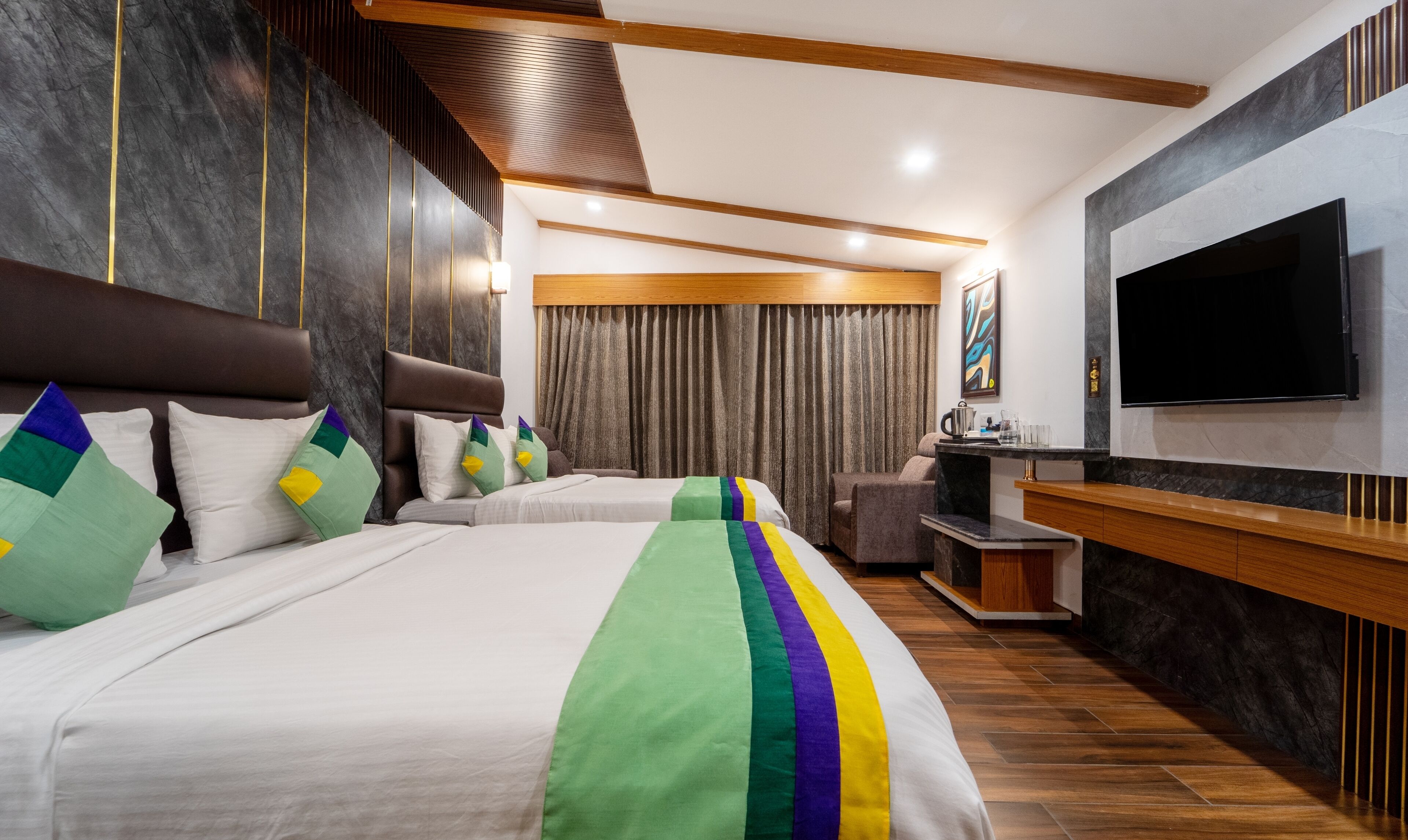 A hotel room with a large bed, a TV, a desk, and a seating area.