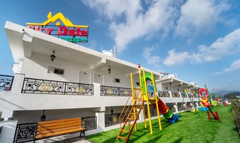 Un hotel con un cartel que dice 'Sunny Dale Suites' y un parque infantil con toboganes y columpios.