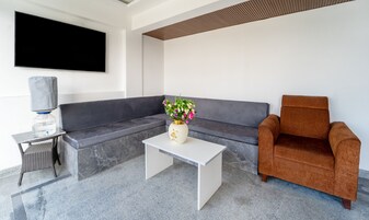 Una sala de estar moderna con un sofá gris, un sillón marrón, una mesa de centro blanca y un jarrón con flores.
