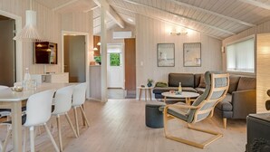A modern interior with a dining area, a living room with sofas and a rocking chair, and a kitchen visible through an open door. - "Barnet" - 2.2km from the sea by Interhome (Blokhus)