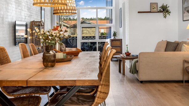 Un comedor moderno con una mesa de madera, sillas de mimbre y un amplio ventanal con vistas al exterior.