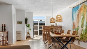 Un comedor moderno con una mesa de madera, sillas de mimbre e iluminación colgante.