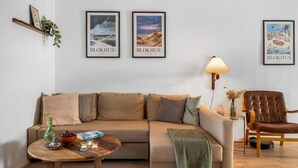 Una sala de estar moderna con un sofá, una mesa de centro, una lámpara y cuadros en la pared.