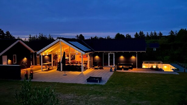A modern house with a large open patio area, a covered outdoor kitchen, and a spacious living room.