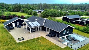 A modern house with a large patio, a swimming pool, and a covered outdoor area.