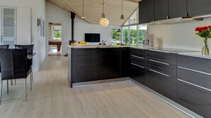 A modern kitchen with a central island, dark cabinetry, and pendant lighting.
