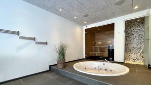 A modern bathroom with a freestanding bathtub, a potted plant, and a glass shower enclosure.