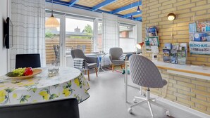 Een moderne kantoorruimte met een ronde tafel, stoelen en een met boekenplanken gevulde bakstenen muur.