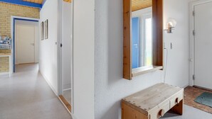 Een hal met een houten bank, een grote spiegel en een deur naar een badkamer.