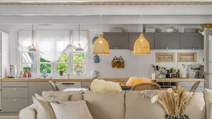 Una cocina moderna con una isla central, luces colgantes y vistas al exterior.
