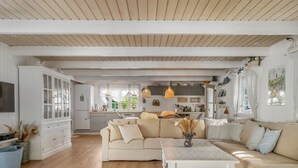 Un espacio habitable amplio con un sofá, una mesa de centro y una cocina al fondo.